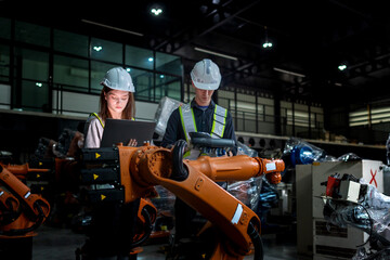 team engineers inspecting on machine with smart tablet. Worker works at heavy machine robot arm. The welding machine with a remote system in an industrial factory. Artificial intelligence concept.