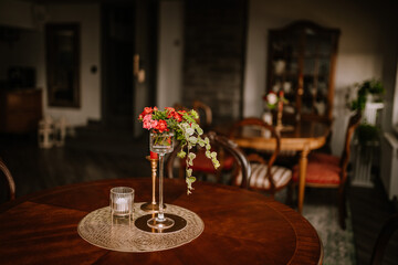 Blome, Latvia - September 11, 2023 - Elegant dining room with floral centerpiece on a round wooden table, surrounded by classic furniture and ambient lighting...
