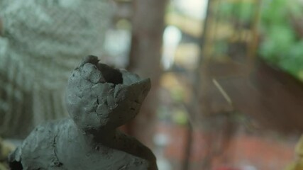 Hands molding clay into a sculpture, creating art in a vibrant setting