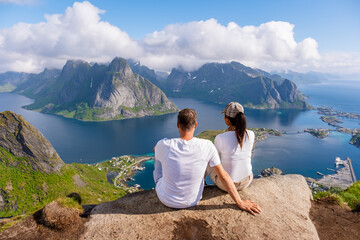 A couple sits on a cliff overlooking a stunning Norwegian fjord, taking in the breathtaking scenery...