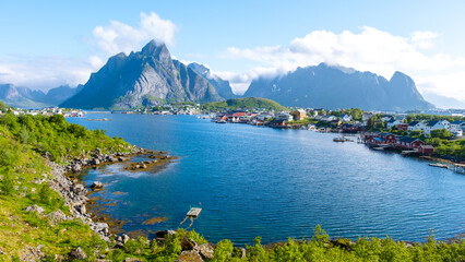 Fototapeta premium Norwegian fjord view with mountains, calm waters, and a quaint village. The scenery embodies the beauty and serenity of Norway. Reine, Lofoten, Norway