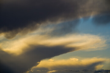 Sunlit dark stormclouds in blue sky