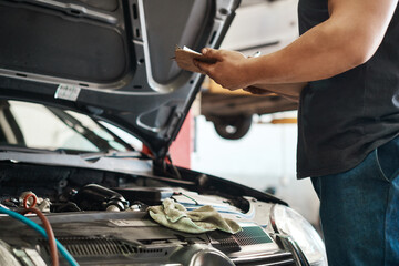 Clipboard, hands and mechanic in workshop with car service, maintenance or auto insurance. Checklist, engine and man in garage for inspection, motor repair and quality assurance at small business.