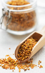 Healthy bee pollen grains.  Bee pollen on a wooden spoon and glass jar.