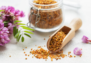 Healthy bee pollen grains.  Bee pollen on a glass jar and acacia flowers.
