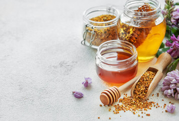 Raw organic bee pollen and honey in jars.