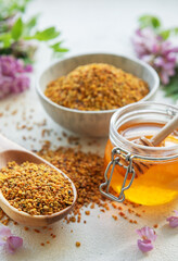 Raw organic bee pollen and honey in jars  and acacia flowers. .