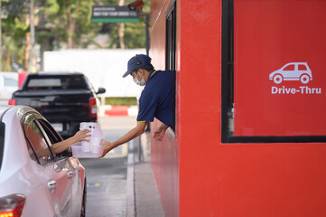 People pick up food and drink glasses from drive-thru counters and take them to eat at home and at...