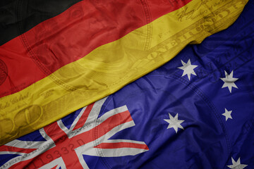 waving colorful flag of germany and national flag of australia on the dollar money background. finance concept.