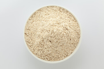 Organic Multi-Grain Flour in a white ceramic bowl. Isolated on a gray background. Top View
