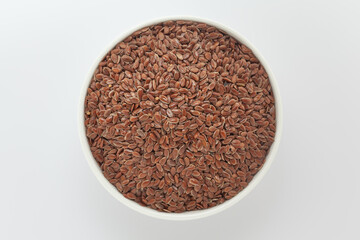 Organic Flaxseeds (Linum usitatissimum), in a white ceramic bowl. Isolated on a grey background. Top View