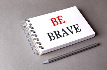 BE BRAVE text on notebook on grey background