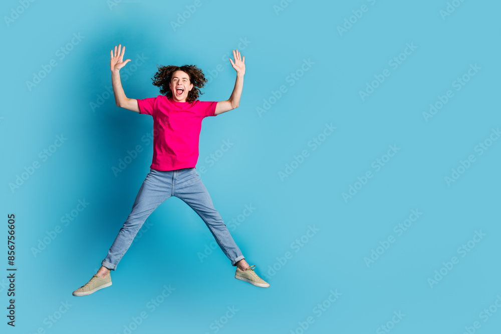 Wall mural Full size photo of nice young man jump empty space wear t-shirt isolated on blue color background