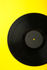Gramophone vinyl record on yellow background. Vertical photo