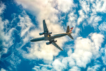 Large jetliner flying through cloudy blue sky with sky background.