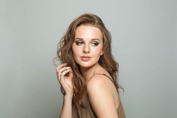 Obraz premium Stylish female face. Woman with makeup, curly hairstyle and fresh skin on white background