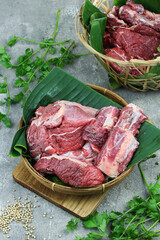 Daging sapi mentah or raw beef on preparation for cooking with some spice. Beef on Eco friendly package and chopping board with wooden rustic background.