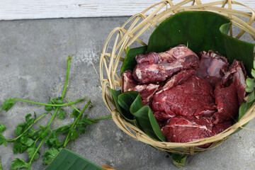 Daging sapi mentah or raw beef on preparation for cooking with some spice. Beef on Eco friendly package and chopping board with wooden rustic background.