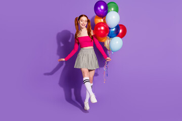 Full length photo of carefree positive girl wear pink top holding balloons bunch empty space isolated purple color background