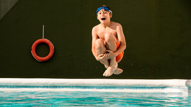 Boy jumping into the water of the pool