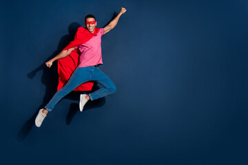 Fototapeta premium Full length body photo advertisement of young superhero guy in red face mask and cape fights against problems isolated on dark blue color background