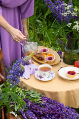Elegant glamour table setting outdoor in the garden. White porcelain cups, teapot with herbal tea,...
