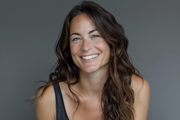 Naklejka premium Portrait of a grinning woman in her 30s smiling at the camera on blank studio backdrop