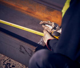 Welder measuring to make iron structure