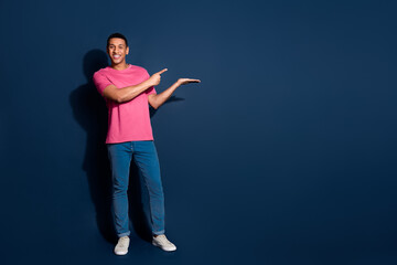 Photo of young funky positive man in pink t shirt advertising holding arm restaurant menu food isolated on dark blue color background