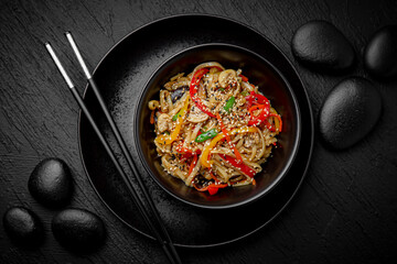 Wok noodles udon chicken with vegetables. Composition on black background. The Art of Japanese Cuisine. Food photography for menu and sushi bar decoration