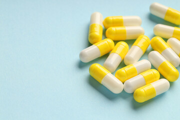 Many antibiotic pills on light blue background, closeup. Space for text