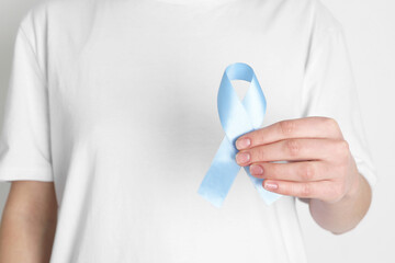International Psoriasis Day. Woman with light blue ribbon as symbol of support on white background, closeup