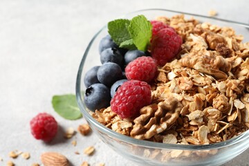 Tasty granola with berries, nuts and mint on grey table, closeup