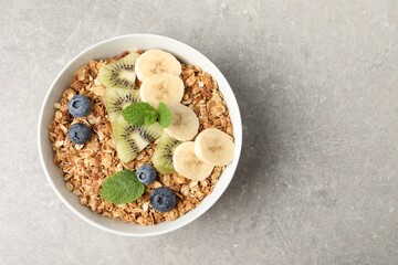 Tasty granola with fresh fruits on grey table, top view. Space for text