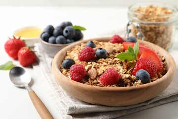 Tasty granola with berries, nuts and mint on white table