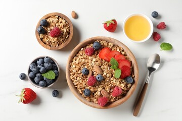 Tasty granola with berries, nuts and mint on white table, flat lay