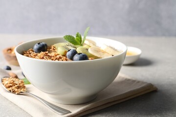 Tasty granola with fresh fruits on grey table