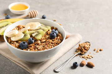 Tasty granola with fresh fruits on grey table. Space for text