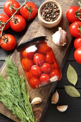 Tasty pickled tomatoes in jar, spices and fresh vegetables on grey wooden table, top view