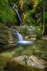 A serene waterfall cascades down mossy rocks in a vibrant forest near Klaus an der Pyrhnbahn,...