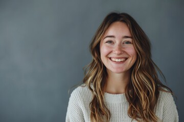 Obraz premium Portrait of a jovial caucasian woman in her 20s smiling at the camera in front of blank studio backdrop