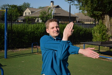 A focused young athlete dynamically performing warm-up drills and stretches outdoors. Clad in...