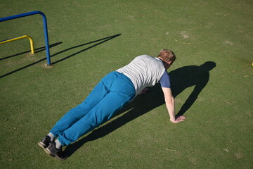 A focused young athlete dynamically performing warm-up drills and stretches outdoors. Clad in...