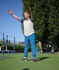 A focused young athlete dynamically performing warm-up drills and stretches outdoors. Clad in...