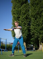 A focused young athlete dynamically performing warm-up drills and stretches outdoors. Clad in...