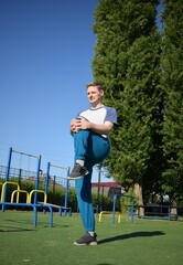 A focused young athlete dynamically performing warm-up drills and stretches outdoors. Clad in...