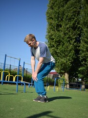 A focused young athlete dynamically performing warm-up drills and stretches outdoors. Clad in...