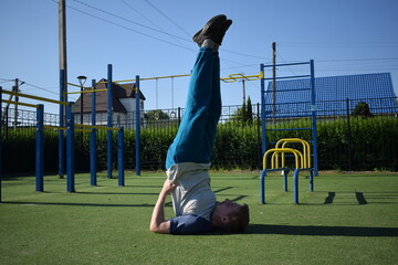 A focused young athlete dynamically performing warm-up drills and stretches outdoors. Clad in...