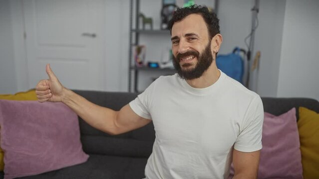 Beaming middle age man in white t shirt doing thumbs up with a proud smile at home, looking the picture of success