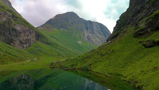 A stunning video of a serene lake in a picturesque mountain valley. Tranquil waters reflect towering mountains, creating a breathtaking natural scene, Norweigan Fjords Stavbergvatnet Urke